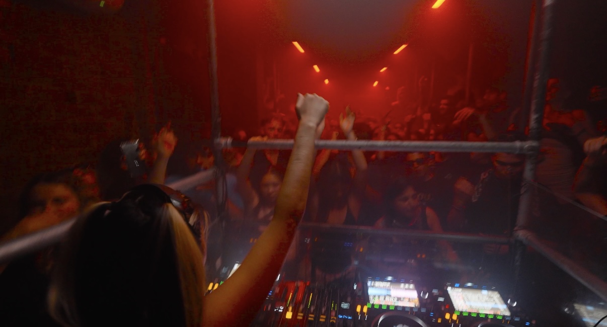 Real DJ booth photographed from behind during a live club set