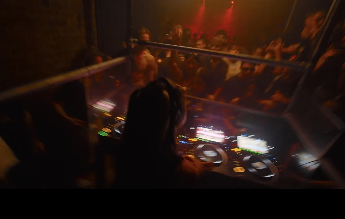 Real DJ booth and crowd photographed from behind the operator during a live event